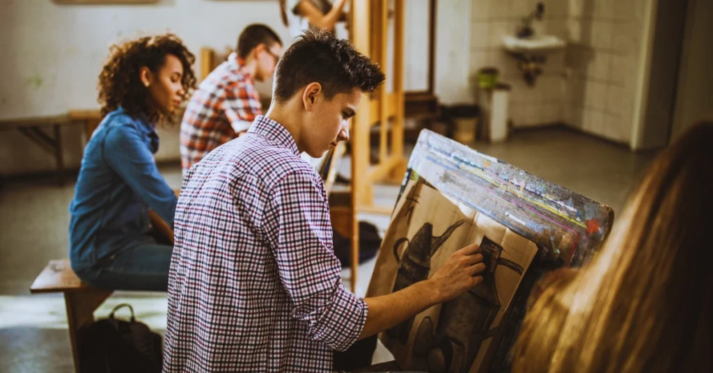 "An image of a diverse group of students learning at a university art class, working intently on their projects as they pursue their arts degrees. The room is filled with easels, canvases, and an array of art supplies, capturing the essence of an academic environment dedicated to developing artistic skills and creativity."